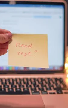 Hand holding sticky note with text in front of laptop and blurred background Stock Photos