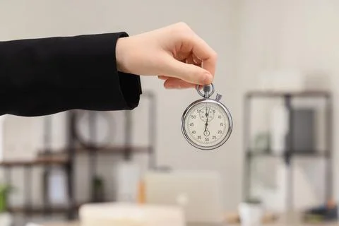 Hand holding stopwatch in office environment Stock Photos