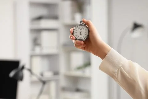 Hand holding a stopwatch in an office setting Stock Photos