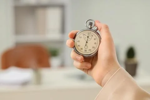 Hand holding a stopwatch in an office setting Stock Photos