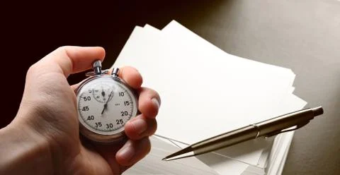 Hand holding stopwatch, stack of paper cards and pen Stock Photos