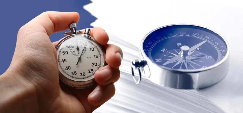 Hand holding stopwatch, stack of paper cards and compass 写真素材
