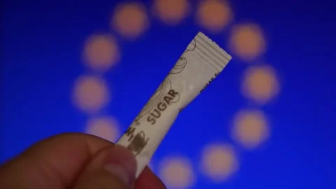 Hand Holding Sugar Packet with Blurred EU Background Lights Video stock 345009915