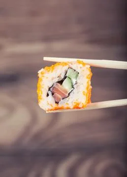 Hand holding sushi roll using chopsticks Stock Photos