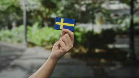 Hand holding swedish flag patch in outdoor city setting symbolizing nationa.. Stock Footage 306853818