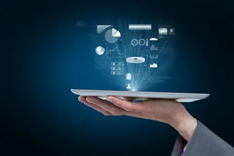 Hand is holding a tablet computer projecting graphics holograms against blue Stock-Fotos