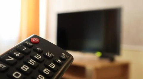 Hand holding a television remote control and surfing programs on television.. Stockfoto's
