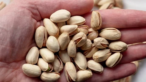 Hand holding textured pistachio nuts Stock Footage 334872507