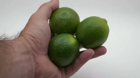 Hand holding three limes in front of white background Stock Footage 287331981