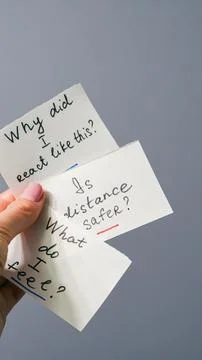 Hand holding three question cards with handwritten text on gray background Stock Photos