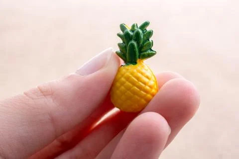 Hand holding a tiny pineapple miniature on a background 写真素材