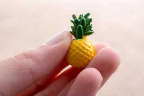 Hand holding a tiny pineapple miniature on a background Foto stock