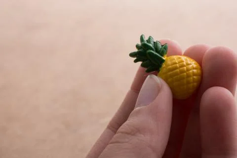 Hand holding a tiny pineapple miniature on a background Foto stock
