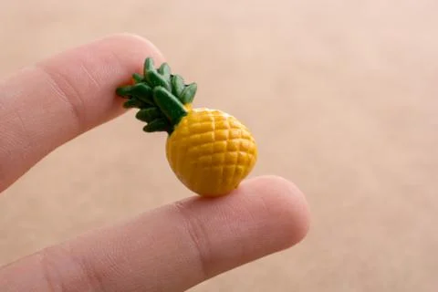 Hand holding a tiny pineapple miniature on a background Stock Photos