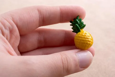 Hand holding a tiny pineapple miniature on a background Stock Photos