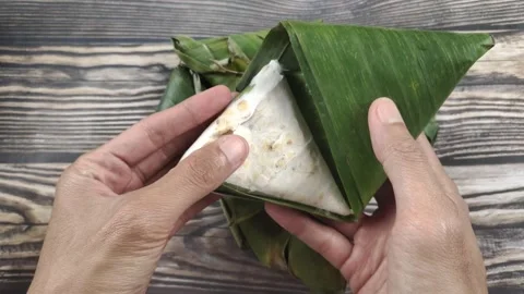 A Hand Holding Triangular Tempeh Wrapped in Banana Leaves Vídeos de archivo 329361958