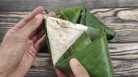 A Hand Holding Triangular Tempeh Wrapped in Banana Leaves Video stock 329361971
