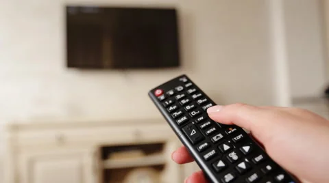 Hand holding TV remote control and changing channels on television Stock Footage 61510978