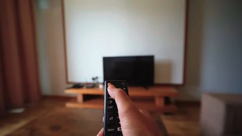 Hand holding tv remote control, changing channel on television Stock Footage 121389963