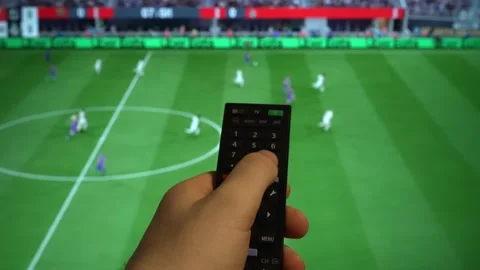 Hand holding TV remote control watching football match on screen. Stock Footage 340556407