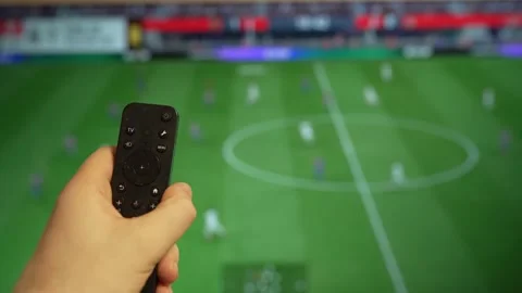 Hand holding TV remote control watching football match on screen. Stock Footage 340556412