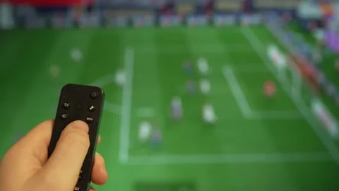 Hand holding TV remote control watching football match on screen. Stock Footage 340556449