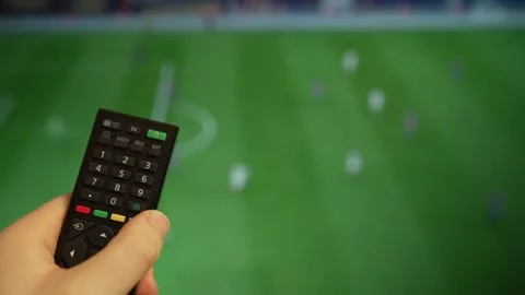 Hand holding TV remote control watching football match on screen. Stock Footage 340556452