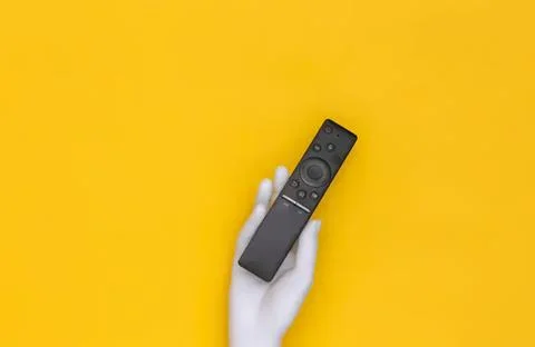 Hand holding a tv remote control on yellow background Stock Photos