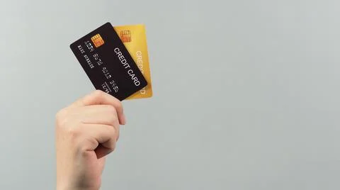 Hand is holding two credit card in black and gold color isolated on grey back Stock Photos