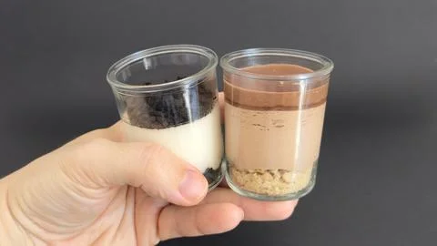 Hand holding two dessert jars side by side Stock Photos