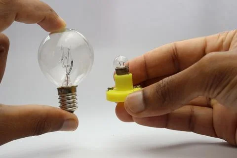 Hand holding two different types of incandescent light bulbs for comparison Stock Photos