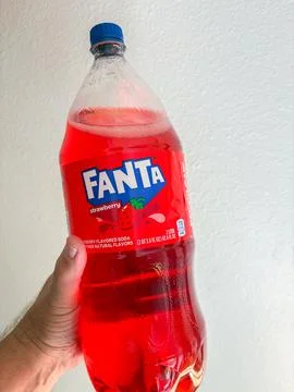 A hand holding a two-liter plastic bottle of red Fanta Strawberry flavored .. Stock-Fotos