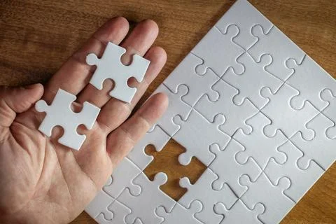 A hand holding two puzzle pieces with one missing Stock Photos