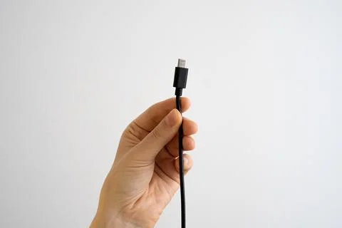 Hand holding USB cable on white background, digital technology concept Stock Photos