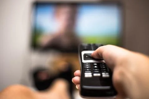 Hand Holding Use Remote Control and Watching TV in House on a colorful flatsc Stock Photos