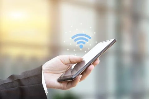 Hand holding using mobile smartphone with wifi icon. Stock Photos