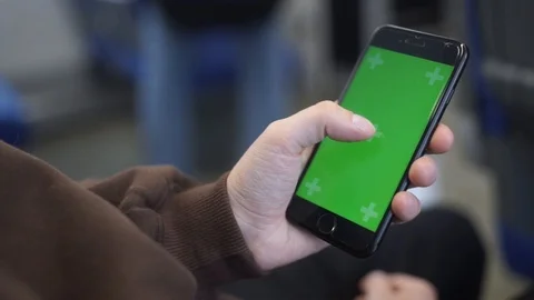 A hand holding (using) a smapthone with a green screen on the train. Close-up Stock Footage 101984144