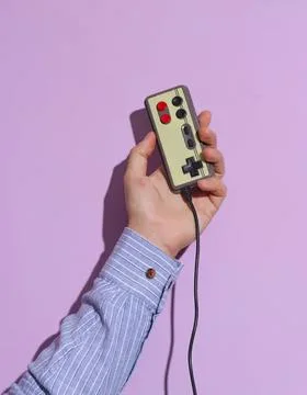 Hand holding vintage game controller on purple background Stock Photos