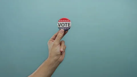 Hand holding vote button on blue background, showing political engagement a.. Stock Footage 315587923