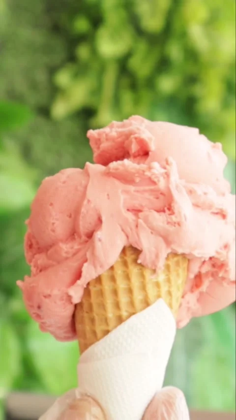 Hand holding waffle cone with three strawberry ice cream scoops outdoor Stock Footage 340528106