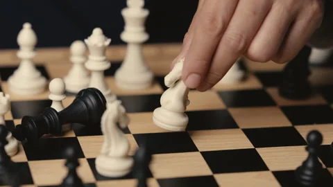 Hand holding a white chess knight taking black king, strategy concept Stock Footage 343430441