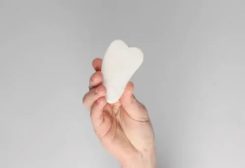 Hand holding a white cloud-shaped sponge on gray background Stock Photos