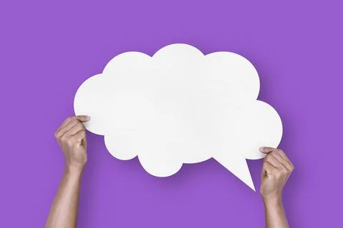 Hand holding white paper cloud shape speech bubble balloon isolated on purp.. Stock Photos