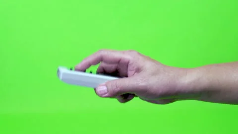 Hand holding white remote with green screen Stock Footage 232608548