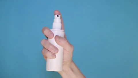 Hand holding a white spray bottle and spraying mist Stock Footage 132457145