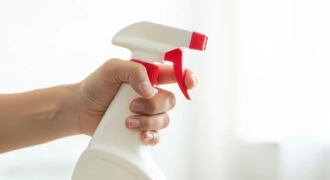 Hand holding white spray bottle with red trigger for cleaning or disinfection Stock Illustration