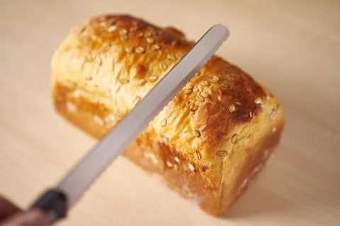 Hand holding a wholemeal bread preparing to slice Stock Photos
