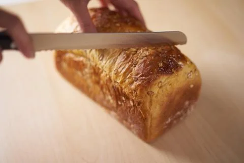 Hand holding a wholemeal bread preparing to slice Stock Photos