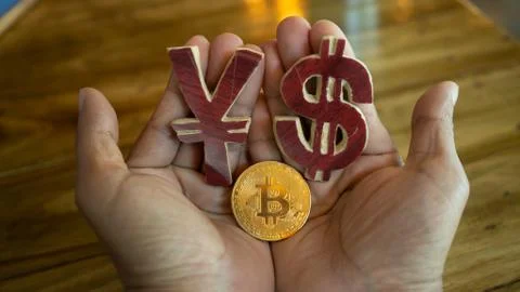 ็Hand holding wood model symbol US Dollar with  Yuan and  Bitcoin coin on wooden Stock Photos