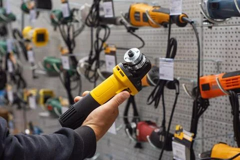 Hand holding yellow angle grinder in hardware store or power tools shop showc Stock Photos